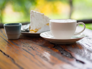 Coffee and cake on table with blurred green background