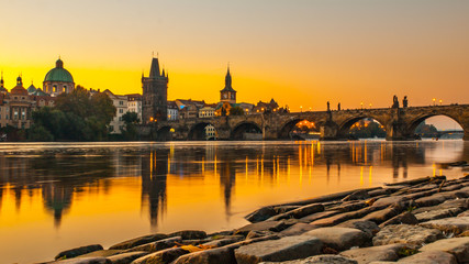 Charles Bridge with Old Town Bridge Tower reflected in Vltava River at morning sunrise time, Prague, Czech Republic.