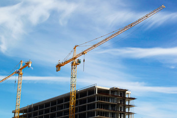 Yellow cranes build against the sky with clouds