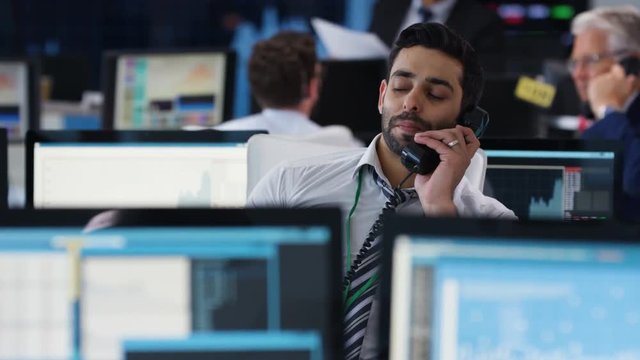  Financial trader in busy stock exchange negotiating a deal over the phone