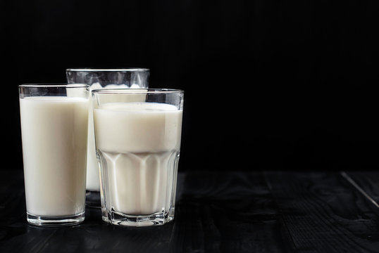 Just three glasses of milk on a black background