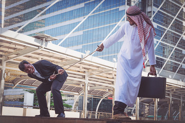 Arab businessmen and businessman playing tug of war on city background