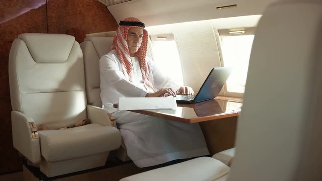  Middle East businessman working on laptop on board private plane