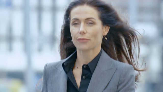 Business Woman in the Tailored Suit Walking on the Busy Big City Street in the Business District, Checks Her Smartphone. Confident Woman on Her Way to do Big Business. 4K UHD.