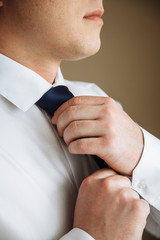 Businessman in white shirt tying the necktie