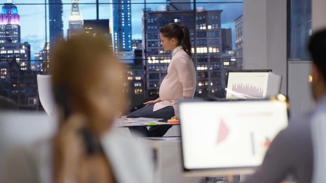  Business team working late, pregnant woman in discussion with male colleague