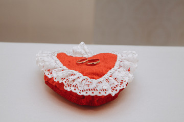 White pillow for wedding rings in a heart