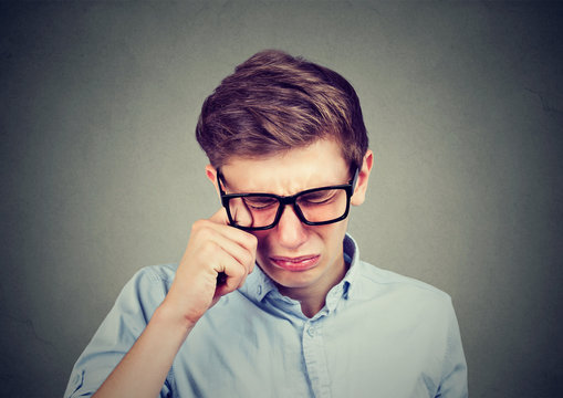 Closeup portrait of a crying teenager man in glasses