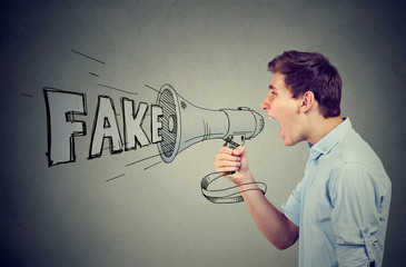 Side profile of a young man screaming in a megaphone spreading fake news