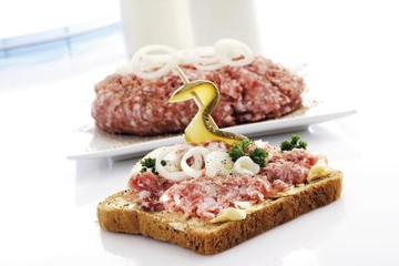 Seasoned minced pork on toast, garnished with onion and a skewered pickle
