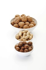 Assorted nuts in ceramic bowls, macadamia nuts, peanuts, hazelnuts