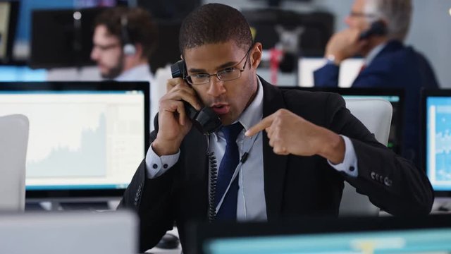  Financial trader in busy stock exchange negotiating a deal over the phone