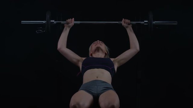  Fit young woman weight training, doing bench press with barbell 