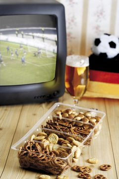 Retro football broadcast - TV broadcast of a game, football hat, glass of beer and a tray of crackers