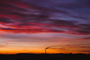 smoke from a chimney on a sunset background and city