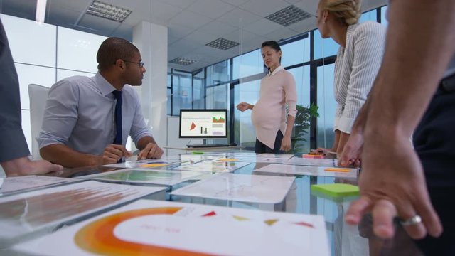  Pregnant businesswoman in a meeting with colleagues looking at financial data