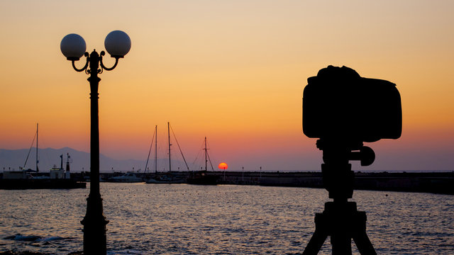 Camera on tripod with sea and sunset in background / Gouves, Crete, Greece 