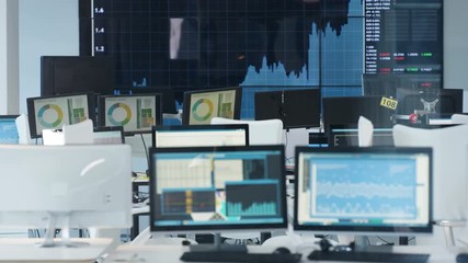 Interior of city financial trading room with screens showing charts and graphs
