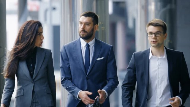 Male and Female Business People Walk and Discuss Business. They're all Working in Central Business District. Shot on RED EPIC-W 8K Helium Cinema Camera.
