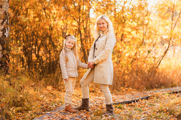 Mom and daughter walk in autumn park