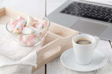 Cup of coffee, twisted marshmallow and laptop notebook