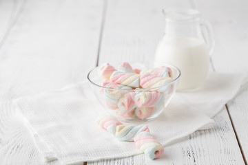 Twisted marshmallows in a cup, over wood background.