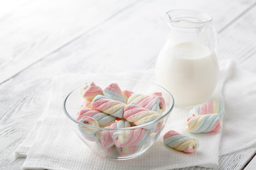 Pile of american twisted marshmallow on table with glass of milk