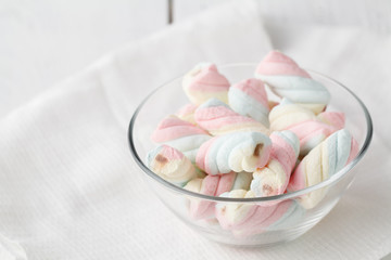 Twisted marshmallows in a cup, over wood background.