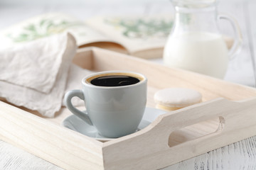 Fototapeta na wymiar Cup of coffee and macaron cakes on tray on white wooden table