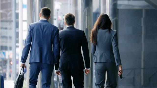 Back View Of Three Business People Walking In The Central Business District. Shot On RED EPIC-W 8K Helium Cinema Camera.