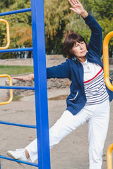 Obraz premium elderly woman performs squatting on summer sports ground