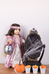 Halloween decoration. An 18 inch doll wearing Halloween costume and holding a trick-or-treating basket. A decorative mirror covered in cobweb. Candy corn in a tiny metal buckets.