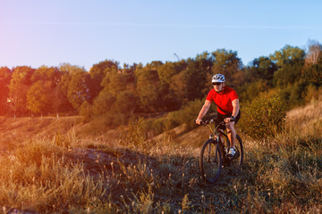 young bright man on mountain bike riding in autumn landscape
