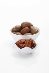 Un-shelled pecan nuts and shelled pecan kernels in porcelain bowls