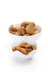 Un-shelled almonds and shelled almond kernels in porcelain bowls