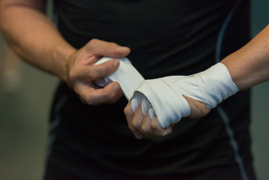 fighter tying tape around his hand preparing to box