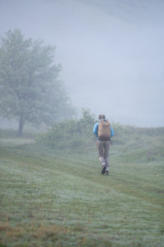 Woman with backpack walking outdoor on a foggy day