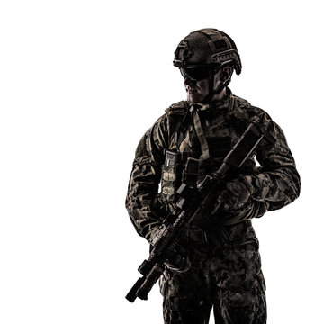 Half length low angle studio shot of special forces soldier in field uniforms with weapons, portrait isolated on white background, front view. Protective goggles glasses are on