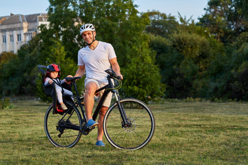 cute girl on bike seat cycling with father in the city