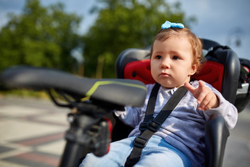 Obraz premium cute happy little baby on bike seat cycling in city park