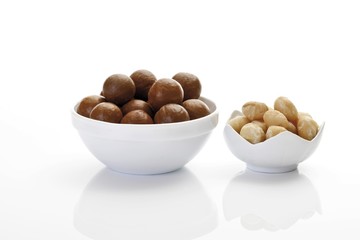 Fototapeta na wymiar Un-shelled macadamia nuts and shelled macadamia kernels in porcelain bowls
