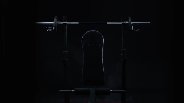  Sleek black gym equipment against black background. Barbell & bench