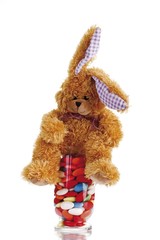 Obraz premium Easter bunny soft toy with candy easter eggs in a glass
