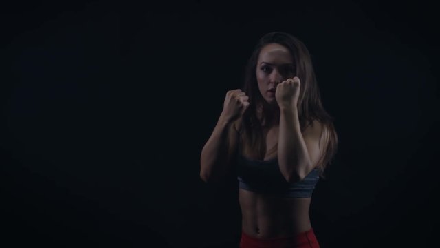  Female boxer training, throwing punches towards camera with bare fists
