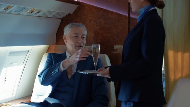  Air hostess serves champagne to businessman traveling on private plane
