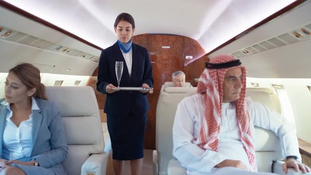  Air hostess serves champagne to business travelers on private plane