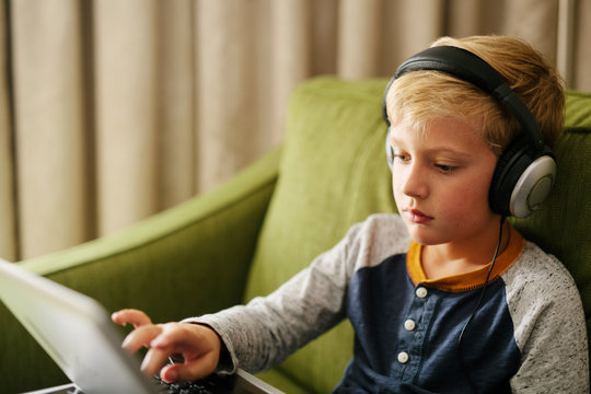 Young boy using laptop with headphones