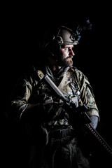 Fototapeta na wymiar Studio contour backlight shot of special forces soldier in uniforms with weapons, portrait on black background