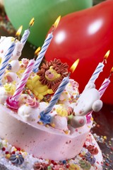 Children's cake with an icing lion, lit candles and a balloon - children's birthday party