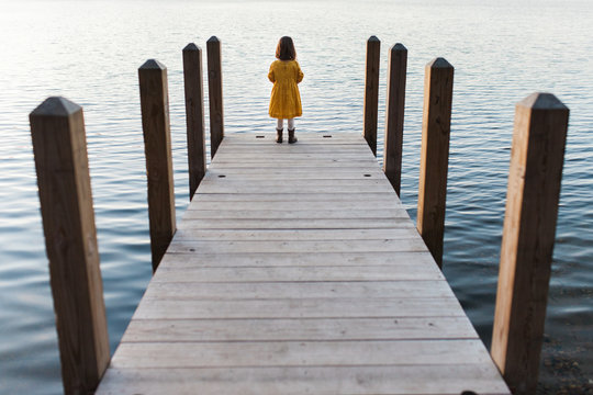 Girl looking out at a lake at the end of a dock